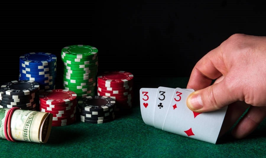 Man holding 3 cards at a Poker table