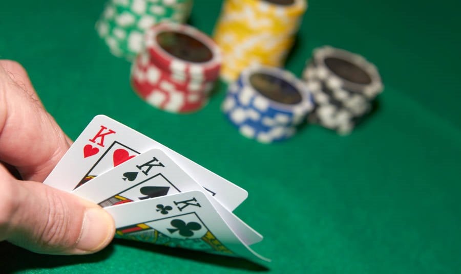 3 poker cards on a Casino Table with poker chips