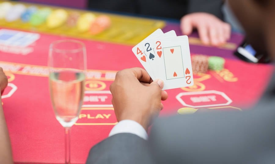 Man holding 3 cards at a Poker table
