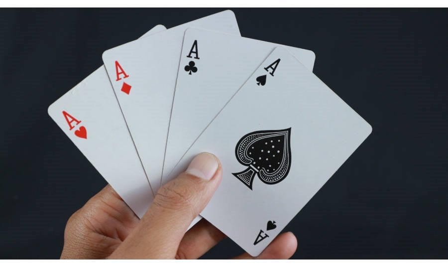Man's hand holding 4 paying cards