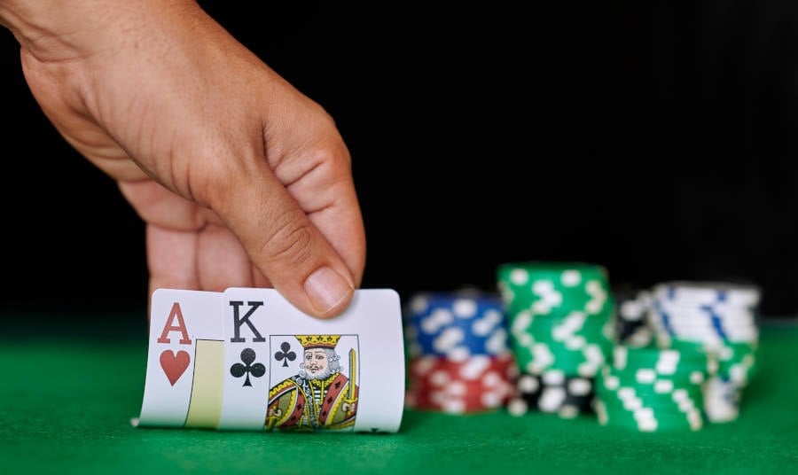 Man's hand checking two cards on a playing table