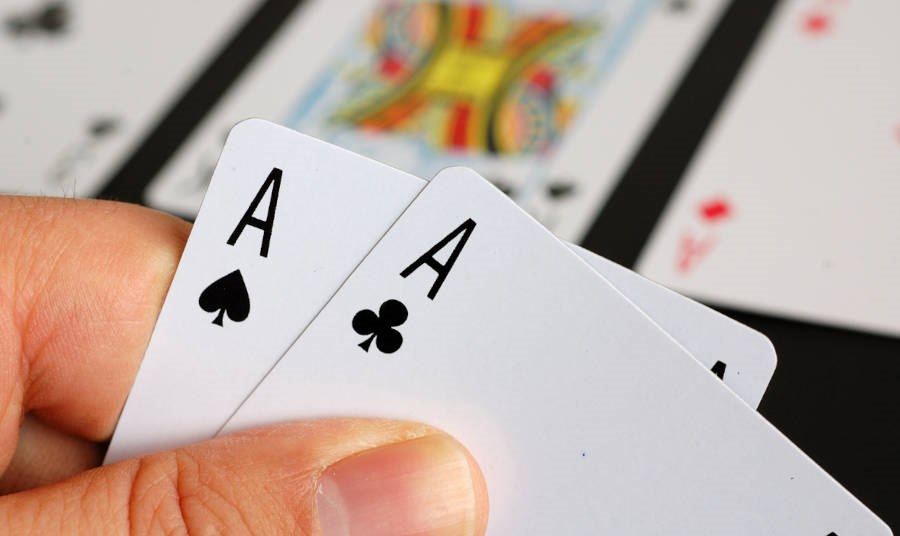 An image of someone holding two aces while playing poker.