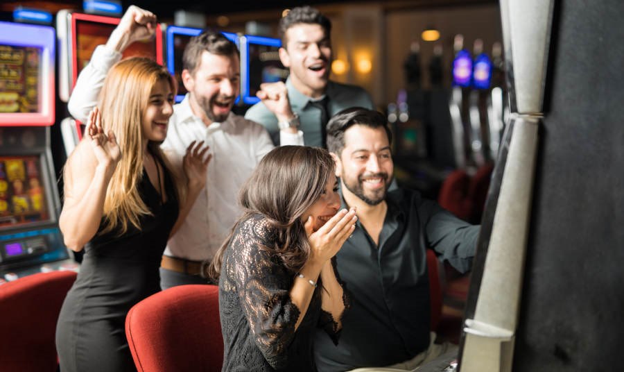 Group of people watching a couple play at a slot machine