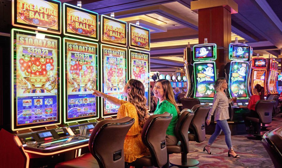 two women sitting at a slot kachine