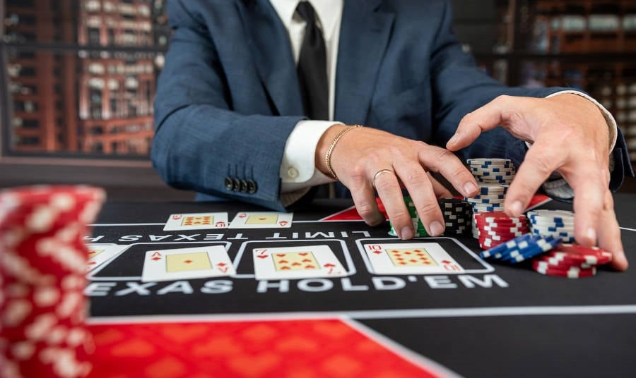 Man at a Texas Hold em table at a casino grabbing chips